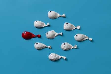 Different business concept.new ideas.Leadership concept with red fish balloon leading among white fishの写真素材
