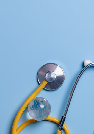 Glass global and stethoscope on light blue background, earth day, world health day, medical and...