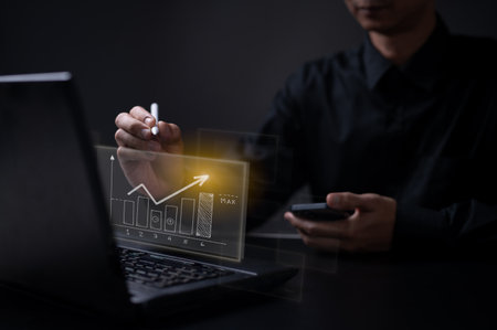 Business man in office drawing a growing graph . futuristic display data of growing business . Marketing strategy and future technology conceptの写真素材