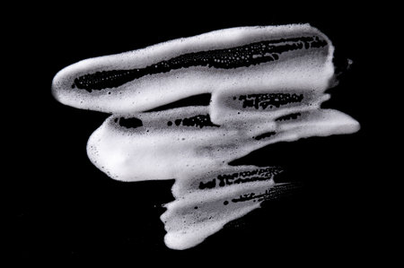 White soapy foam texture. Shampoo foam with bubbles.White facial foam creamy bubble soap sponge isolated on black background.の写真素材