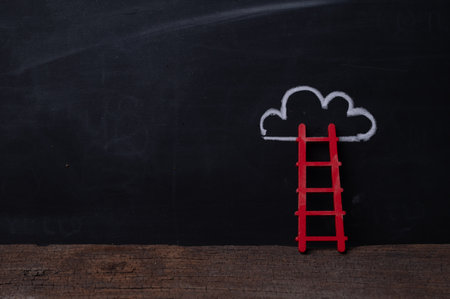 Wooden ladder leaning on blackboard with chalk drawn cloud