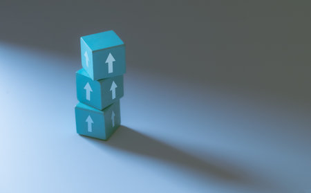 Business growth concept. Blocks with upward arrows arranged as ascending steps on blue background, symbolizing progress, success, and development. Copy space.の写真素材