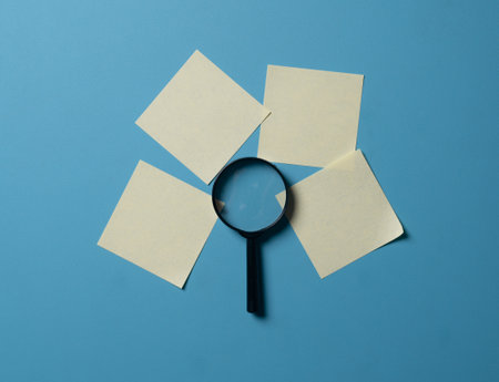 Magnifying glass and sticky notes on blue. Search conceptの写真素材