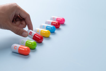 Hand Selecting Colorful Vitamin Capsules on Blue Background,VITAMIN Bの写真素材