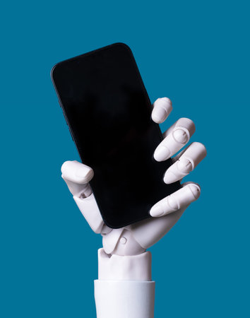 AI Robot Hand Holding Smartphone with Black Blank Screen on Blue Backgroundの写真素材