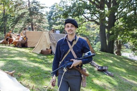 Conneaut, Ohio/USA - August 18th, 2017/A french resistance reenactor with a sten gun poses in front of his tent camp wearing period clothing on a sunny day. This event is a WWII reenactment of D-Day.のeditorial素材