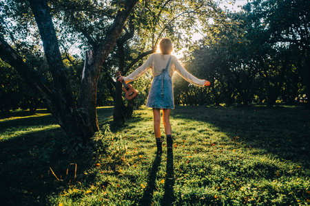 Happy woman at sunset in nature in summer with arms open, jumps for joy