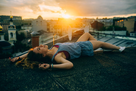Beautiful woman rests on the roof, hipster portrait outdoors, sunset time, city, rest time, light, hipster photo, happy face, smile, crazy girl, brunette hairの写真素材
