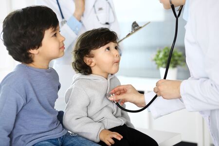 Doctor examining a child patient by stethoscope. Cute arab boy at physician appointment. Medicine and healthcare conceptの写真素材