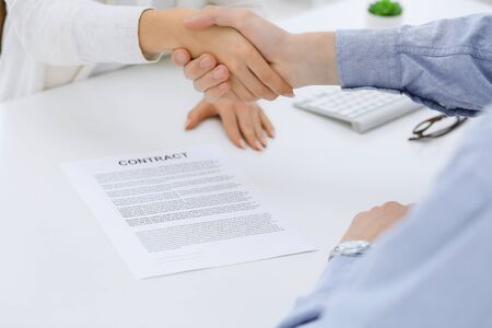 Business people shaking hands at meeting or negotiation after contract discussing. Businessman and woman handshake at office while sitting at the desk. Success conceptの写真素材