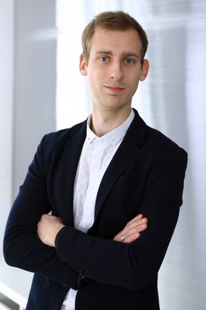 Businessman standing and looking at camera in office. Headshot of casual dressed guyの写真素材