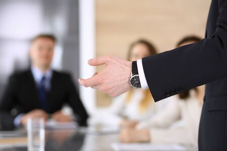 Business presentation. Businessman giving speech to colleagues and partners at corporate meeting or conference, close-up of speaker handsの写真素材