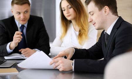 Business people or lawyers discussing questions at meeting in modern office. Unknown businessman and woman with colleague sitting and working at the glass desk. Teamwork and partnership conceptの写真素材