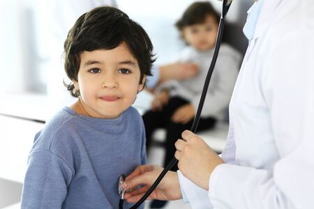 Doctor examining a child patient by stethoscope. Cute arab boy at physician appointment. Medicine and healthcare conceptの写真素材