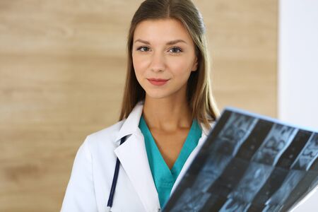 Doctor woman standing and looking at camera. Physician at work, studio portrait at medical background. Medicine and health care conceptの写真素材