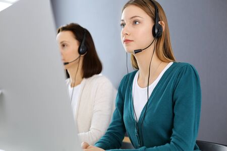 Call center. Group of operators at work. Focus on beautiful woman receptionist in headset at customer service office. Business conceptの写真素材