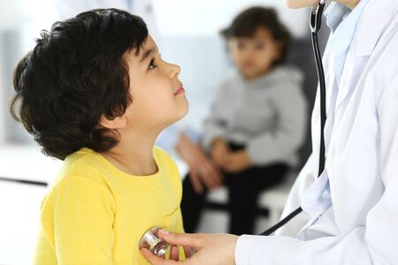 Doctor examining a child patient by stethoscope. Cute arab boy at physician appointment. Medicine and healthcare conceptの写真素材