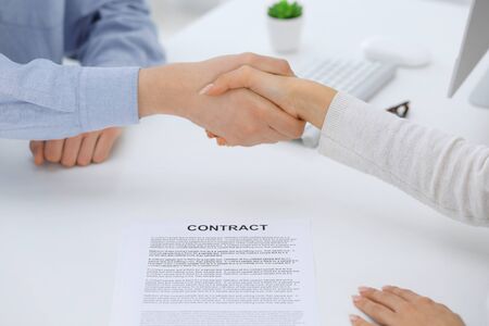 Business people shaking hands at meeting or negotiation after contract discussing. Businessman and woman handshake at office while sitting at the desk. Success conceptの写真素材