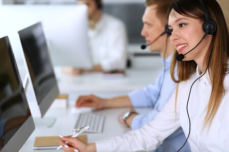 Call center. Group of diverse operators at work. Focus on beautiful asian woman in headset at customer service office. Business conceptの写真素材