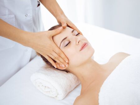 Young and blonde woman enjoying facial massage in spa salon. Beauty conceptの写真素材