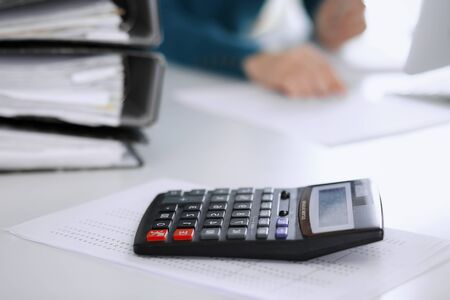 Calculator and binders with papers are waiting to be processed by business woman or bookkeeper...