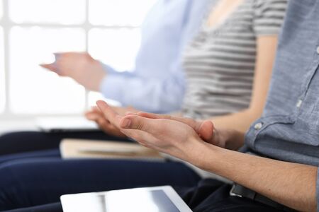 Business people clapping at meeting or conference, close-up of hands. Group of unknown businessmen and women in modern white office. Success teamwork, corporate coaching and applause conceptの写真素材