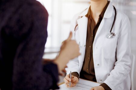 Doctor and patient discussing current health examination while sitting in sunny clinic. Perfect medical service in hospitalの写真素材