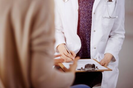 Doctor and patient discussing current health examination while sitting in sunny clinic. Perfect medical service in hospitalの写真素材