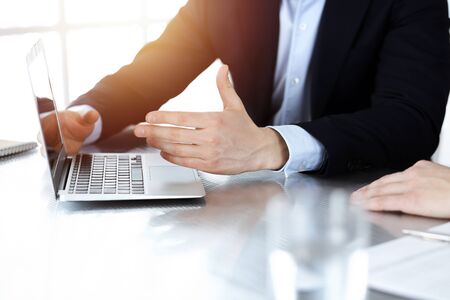 Business people using laptop computer while working together in sunny modern office. Unknown businessman with colleague at workplace. Teamwork and partnership conceptの写真素材