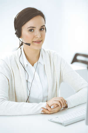 Call center. Casual dressed woman sitting in headset at customer service office. Group of operators at work. Business conceptの写真素材
