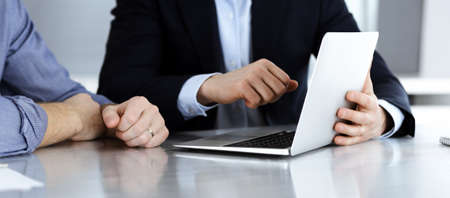Business people using tablet computer while working together at the desk in modern office. Headshot...