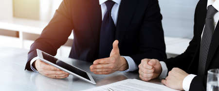 Business people using tablet computer while working together in sunny modern office. Unknown...
