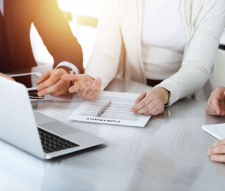 Business people discussing contract while working together in sunny modern office. Unknown businessman and woman with colleagues or lawyers at meetingの写真素材