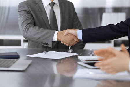 Unknown business people are shaking hands after contract signing in modern office, close-up....