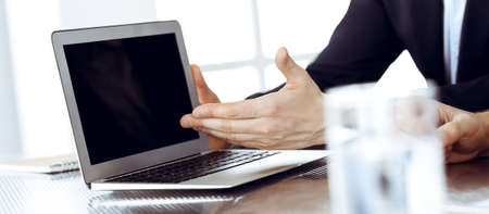 Business people using laptop computer while working together at the desk in modern office. Unknown businessman or male entrepreneur with colleague at workplace. Teamwork and partnership conceptの写真素材