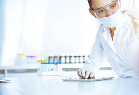 Female laboratory assistant analyzing test tube with blue liquid. Medicine, health care and researching conceptの写真素材