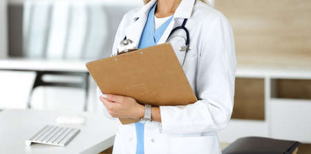 Unknown woman-doctor at work in clinic. Female physician controls medication history record and medical exam results, close-up. Medicine conceptの写真素材