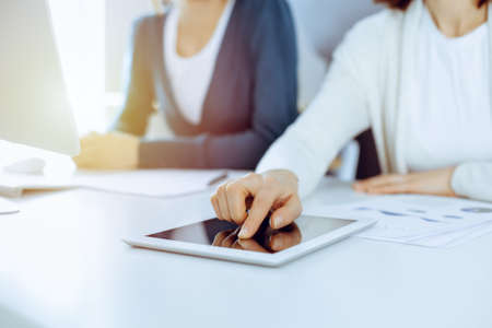 Businesswoman pointing at tablet computer screen while giving presentation to her female colleague....