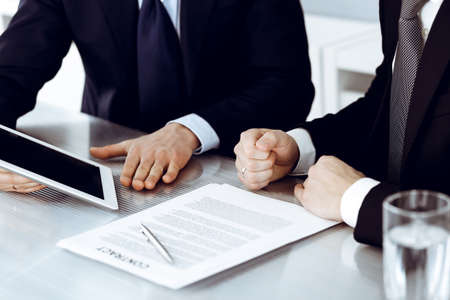 Business people using tablet computer while working together in modern office. Unknown businessman with colleague at workplace. Teamwork and partnership conceptの写真素材