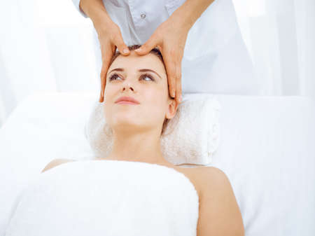 Young and blonde woman enjoying facial massage in spa salon. Beauty conceptの写真素材