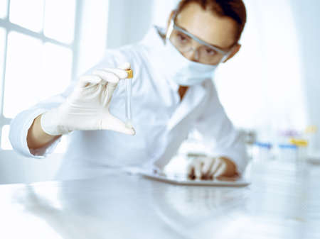 Female laboratory assistant analyzing a blood sample at hospital. Medicine, health care and researching conceptの写真素材