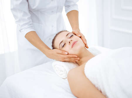 Young and blonde woman enjoying facial massage in spa salon. Beauty conceptの写真素材