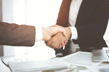 Unknown diverse business people are shaking hands finishing contract signing in sunny office, close-up. Business handshake conceptの写真素材