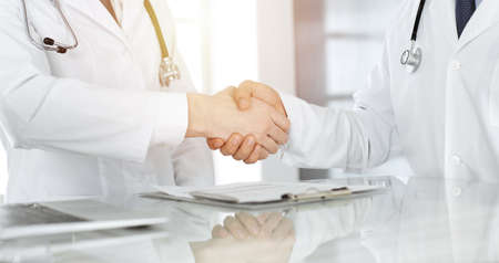 Two doctors are shaking hands as agreement about patients treatment, close-up. Medical help, medicine conceptの写真素材