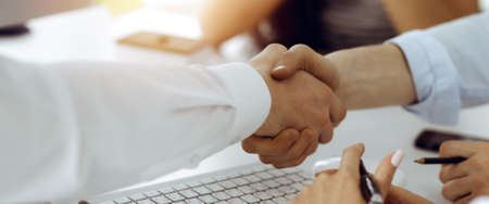 Two businessmen shaking hands in sunny office, close-up. Colleagues applauding of success meeting...