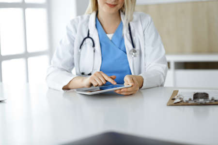 Unknown woman-doctor standing in clinic and using tablet pc, close-up. Data and best service in medicine and healthcareの写真素材