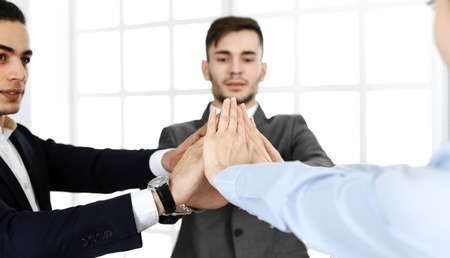 Business people group showing teamwork, joining hands and giving five to each other in modern...