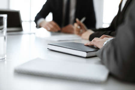 Unknown businessmen and woman sitting, working and discussing questions at meeting in modern office,...
