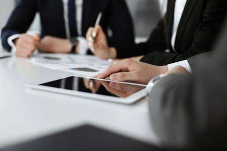 Unknown businessmen and woman sitting, working and discussing questions at meeting in modern office, close-upの写真素材