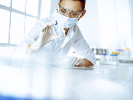 Female laboratory assistant analyzing a blood sample at hospital. Medicine, health care and...